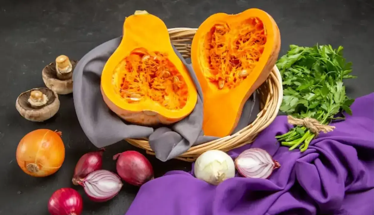 Courge de Hongrie coupée en deux dans un panier, entourée d'oignons, de champignons et de persil frais.