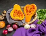 Courge de Hongrie coupée en deux dans un panier, entourée d'oignons, de champignons et de persil frais.