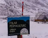 Panneau "Polar Permaculture Urban Farm" devant un dôme géodésique enneigé, rappelant la réserve mondiale de semences du Svalbard.