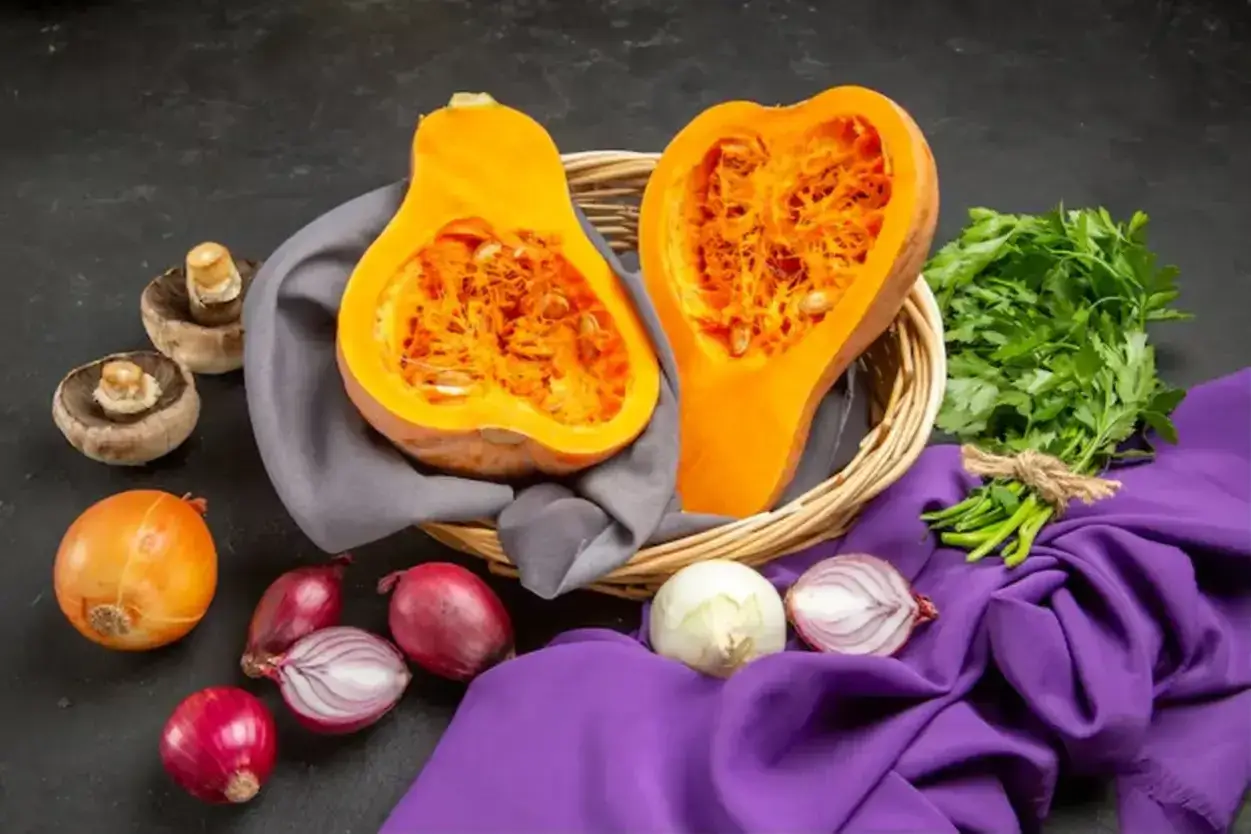 Courge de Hongrie coupée en deux dans un panier, entourée d'oignons, de champignons et de persil frais.
