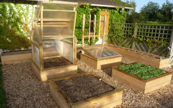 Plusieurs carrés potagers en bois, certains avec des mini-serres, prêts à fabriquer un jardin productif.